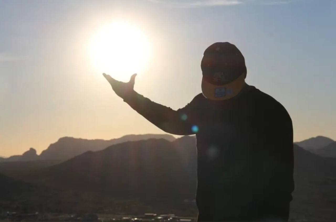 A figure standing against a mountain sunset